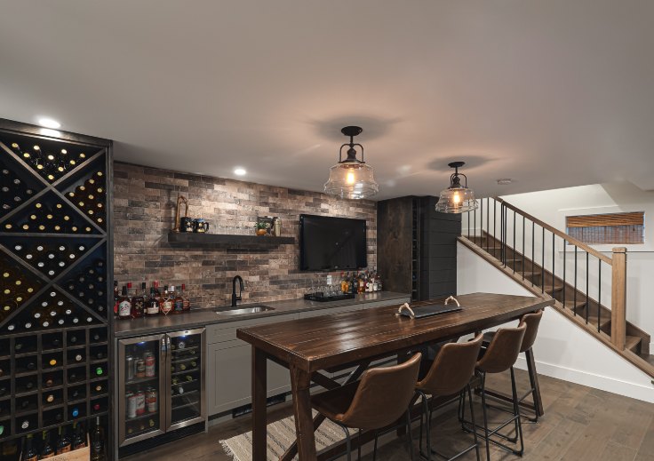 Basement bar with a brick backsplash, beverage coolers, wine racking and a high-top table with stools