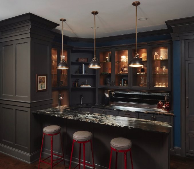 Dark-cabinet home bar with glass-front display cabinets, brass pendant lights, a stone counter and three stools