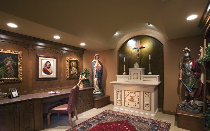 Home chapel with a white and gold altar in an arched niche, a crucifix, statues and framed sacred art