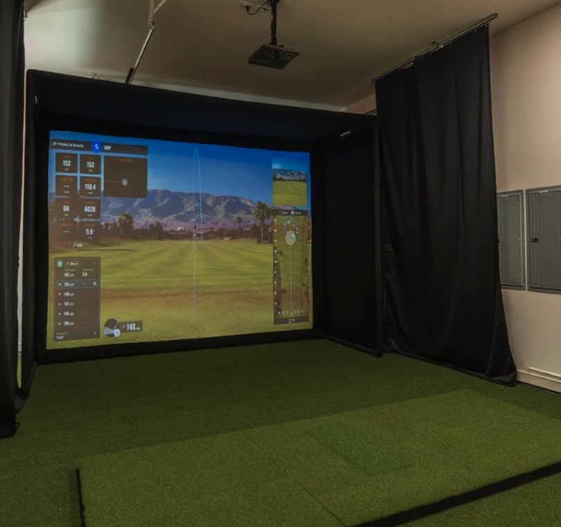 Golf simulator room with an impact screen, black enclosure curtains, ceiling projector and turf