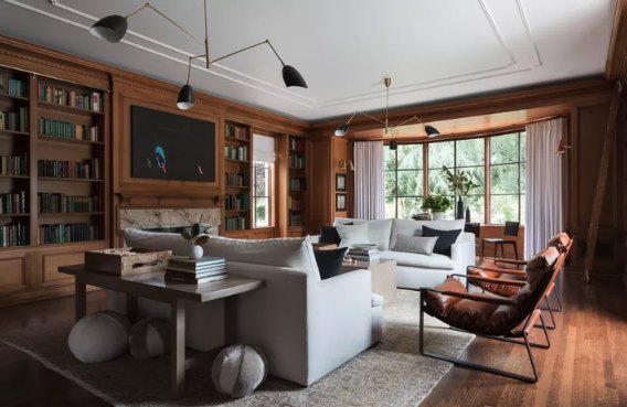 Wood-paneled library and sitting room with built-in bookshelves and a fireplace