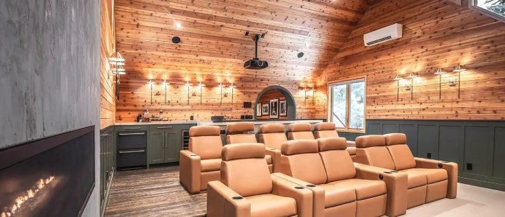 Cedar-paneled home theater with rows of leather recliners and a ceiling projector