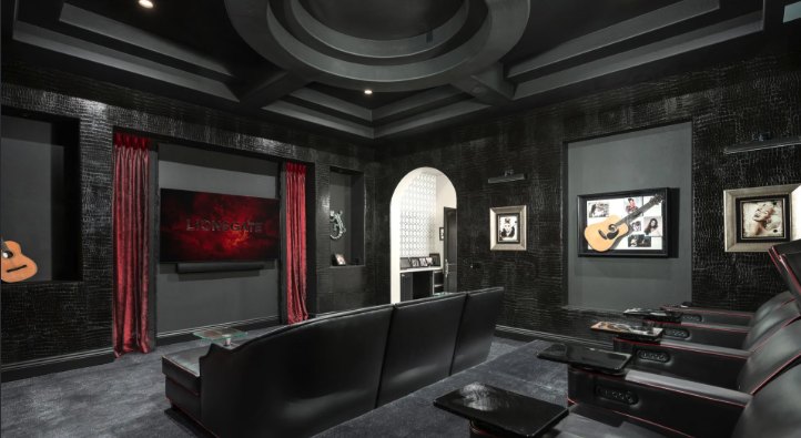 Dark home theater with a coffered ceiling, textured black walls and red drapes