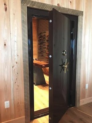 Open vault door set into a wood-paneled wall, with a display room behind it
